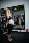 Pregnant woman performing stretching exercise in gym — Stock Photo