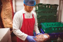 Primo piano del macellaio che organizza carne in casse in macelleria — Foto stock