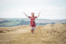 Mulher loira despreocupada em pé no campo com os braços abertos — Fotografia de Stock