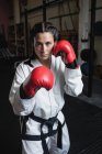 Porträt einer Boxerin in roten Boxhandschuhen, die im Fitnessstudio in die Kamera blickt — Stockfoto
