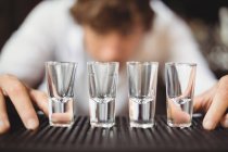 Barman préparant et doublant des verres pour boissons alcoolisées sur le comptoir du bar au bar — Photo de stock