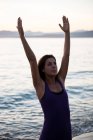 Mulher atraente praticando ioga na praia no dia ensolarado — Fotografia de Stock