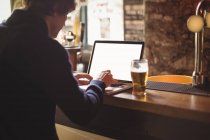 Homem usando laptop no balcão de bar — Fotografia de Stock