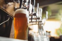 Gros plan de verre à bière avec mousse dans un bar — Photo de stock