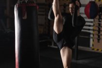 Boxer praticando boxe com saco de perfuração no estúdio de fitness — Fotografia de Stock