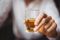Крупним планом бармен тримає віскі постріл склянки біля барної стійки в барі — стокове фото
