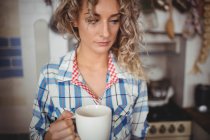 Beautiful woman having coffee in kitchen at home — Stock Photo