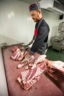 Açougueiro cortando as costelas de carcaça de porco no açougue — Fotografia de Stock