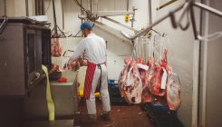 Açougueiro trabalhando na sala de armazenamento de carne no açougue — Fotografia de Stock