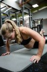 Pregnant woman doing push-ups in gym — Stock Photo