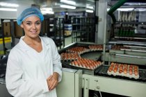 Женщины-сотрудники, стоящие рядом с конвейерной лентой на яйцефабрике — стоковое фото