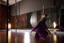 Sensual bailarina polaca practicando pole dance en estudio - foto de stock
