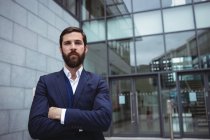 Portrait of businessman standing with arms crossed outside office — Stock Photo