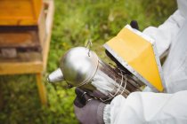 Imagem recortada do apicultor usando fumante de abelha em campo — Fotografia de Stock