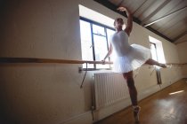 Vista ad angolo basso della Ballerina che pratica danza classica alle sbarre in studio — Foto stock