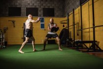 Boxers tailandeses praticando boxe no ginásio escuro — Fotografia de Stock