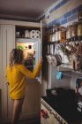 Frau sucht zu Hause im Kühlschrank in Küche nach Essen — Stockfoto