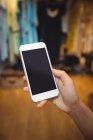 Рука жінки, що використовує мобільний телефон в магазині одягу — стокове фото