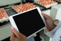 Кадроване зображення жіночих співробітників, що використовують цифровий планшетний поруч з конвеєра на заводі — стокове фото