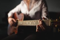 Sección media de la mujer tocando una guitarra en la escuela de música - foto de stock