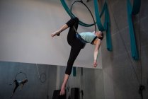 Gimnasta femenina que realiza gimnasia en el aro en el gimnasio - foto de stock