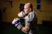 Handsome muay thai boxer practicing boxing in gym — Stock Photo