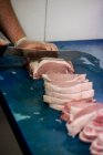 Руки мясника режут мясо на рабочем столе в мясной лавке — стоковое фото