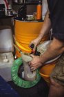 Mécanicien verser de l'huile dans gallon à l'atelier — Photo de stock