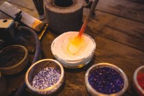 Close-up of attaching colored glass to a piece of hot molten glass at glassblowing factory — Stock Photo