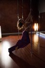 Vista laterale della ballerina polacca che pratica la pole dance in studio — Foto stock
