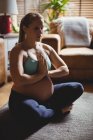 Беременная женщина, занимающаяся йогой в гостиной дома — стоковое фото
