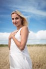 Portrait of beautiful blonde woman standing in field and looking at camera — Stock Photo