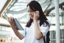 Молодая женщина разговаривает по мобильному телефону во время использования цифрового планшета — стоковое фото