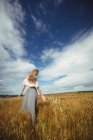 Visão traseira da mulher tocando trigo no campo — Fotografia de Stock