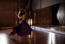 Vista lateral da dançarina Pole praticando pole dance em estúdio — Fotografia de Stock