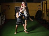 Vista lateral de dos boxeadores tailandeses luchando en el gimnasio - foto de stock