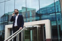 Бізнесмен говорити на мобільний телефон у вході Офісна будівля — стокове фото