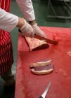 Mains de boucher tranchant de la viande rouge à la boucherie — Photo de stock