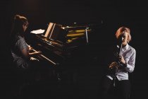 Две студентки играют на кларнете и фортепиано в студии — стоковое фото