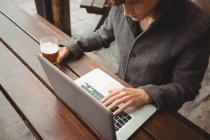 Mann benutzt Laptop, während er Bier in Bar trinkt — Stockfoto
