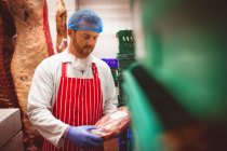 Macellaio che organizza carne in casse in macelleria — Foto stock