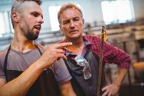 Glassblowers interacting with each other at glassblowing factory — Stock Photo