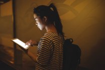 Молодая женщина, используя цифровой планшет в проходе ночью — стоковое фото