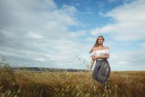 Mulher em pé no campo de trigo no dia ensolarado no campo — Fotografia de Stock