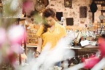 Женщина смотрит на винтажные украшения в антикварном магазине — стоковое фото