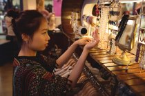 Стильная женщина выбирает украшения в антикварном ювелирном магазине — стоковое фото