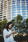 Молода жінка використовує мобільний телефон на вулиці — стокове фото