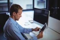 Uomo d'affari che utilizza tablet digitale e PC desktop in ufficio — Foto stock