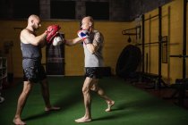 Seitenansicht zweier sportlicher thailändischer Boxer beim Training im Fitnessstudio — Stockfoto