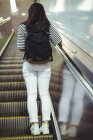 Vista trasera de la mujer de pie en la escalera mecánica - foto de stock